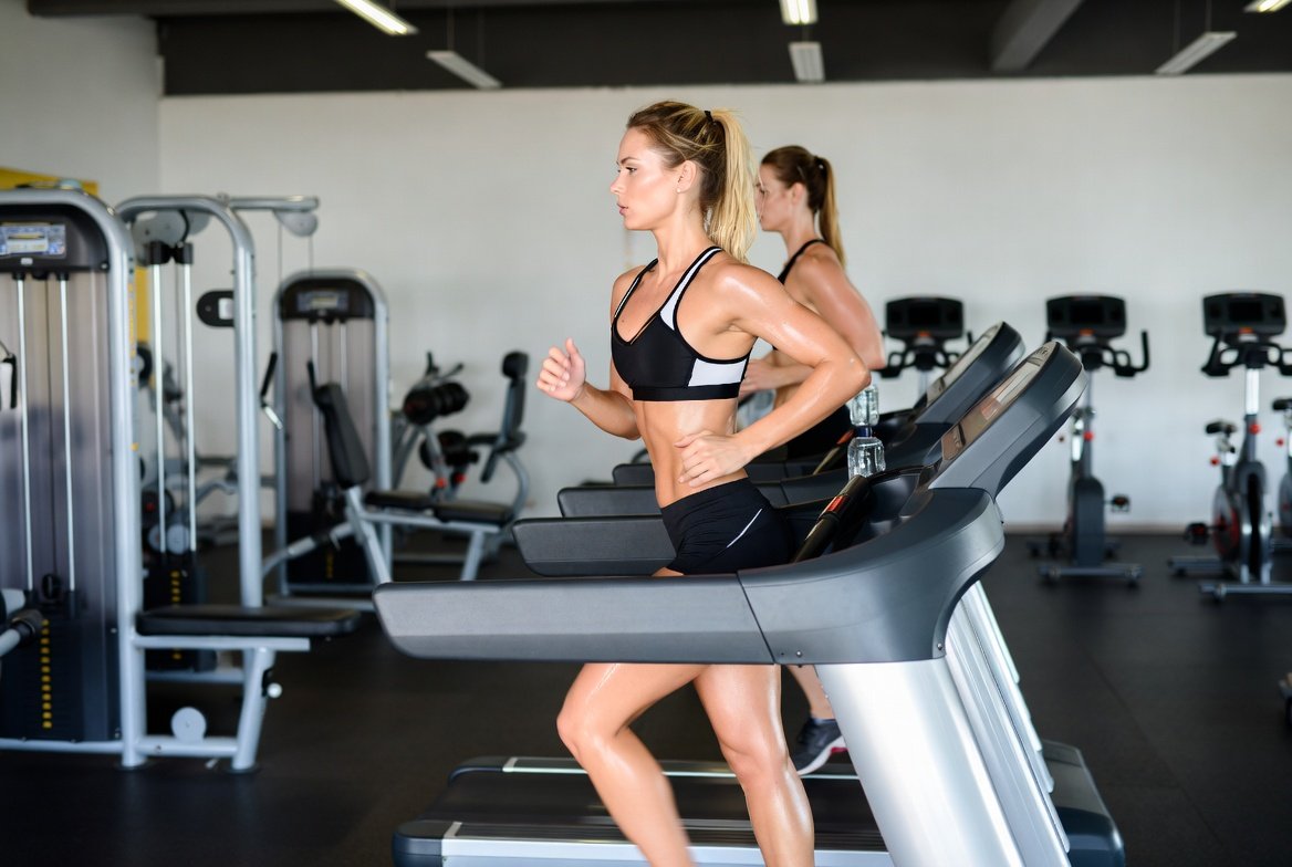 Woman running on treadmill in gym performing cardio exercise to improve heart health and cardiovascular fitness